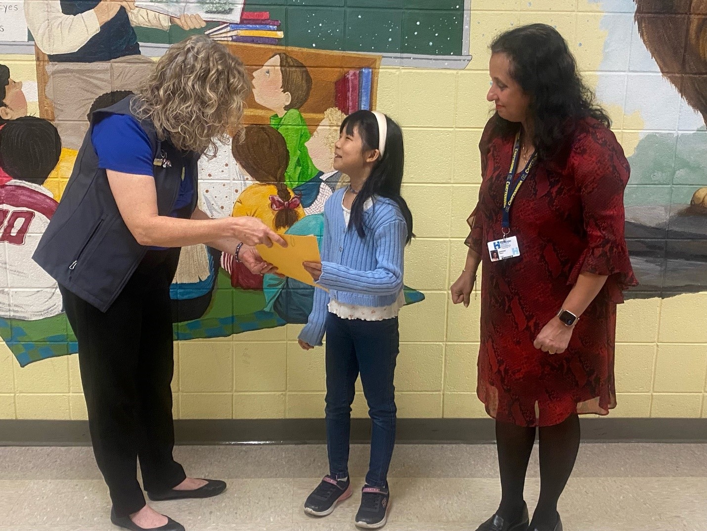 CCU CEO, Joy Traxler handing Eunseol her award with Teacher, Vandana Taneja